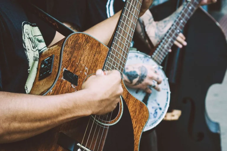 Close-up of hands playing an acoustic guitar and a banjo side by side