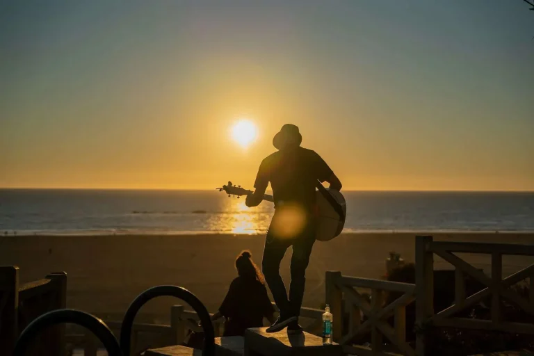 Acoustic guitarist performing on the beach at sunset near the Alabama Gulf Coast