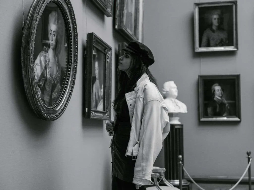 A visitor viewing framed portrait paintings in an art museum gallery
