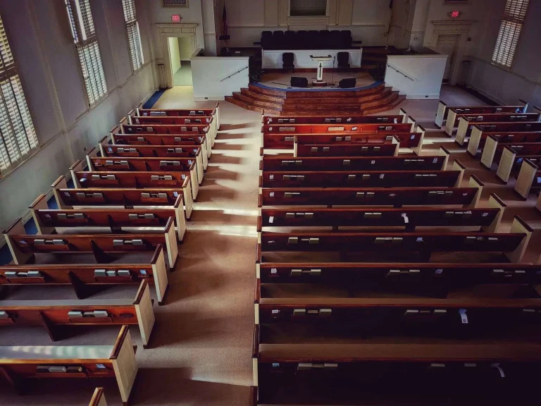 Empty Baptist church sanctuary with rows of wooden pews facing a simple pulpit and cross