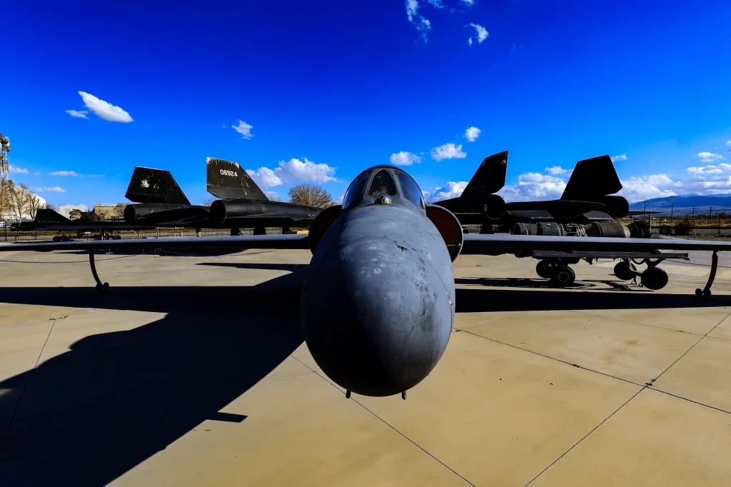 A Blackbird-family reconnaissance jet on outdoor static display, nose toward the camera, with two more Blackbird aircraft parked behind it under a blue sky