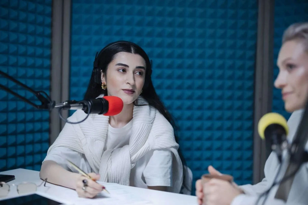 Two people speaking into microphones during an interview in a radio broadcast studio