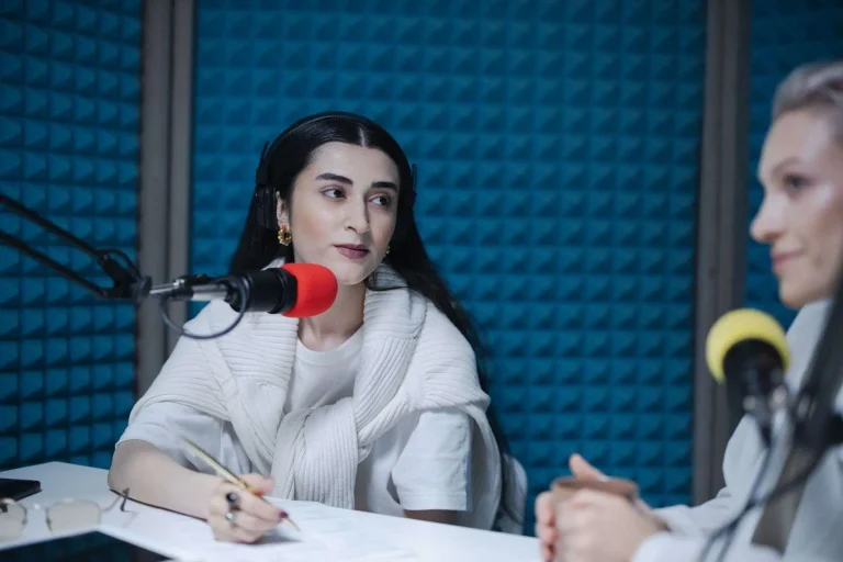 Two people speaking into microphones during an interview in a radio broadcast studio