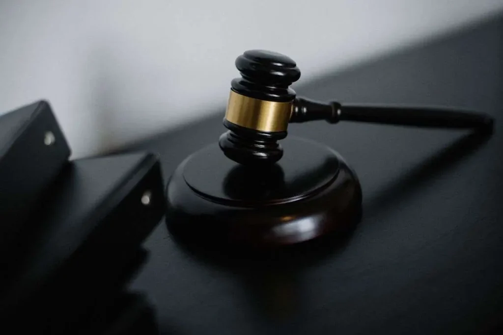 A judges gavel resting on its sound block on a dark wooden desk
