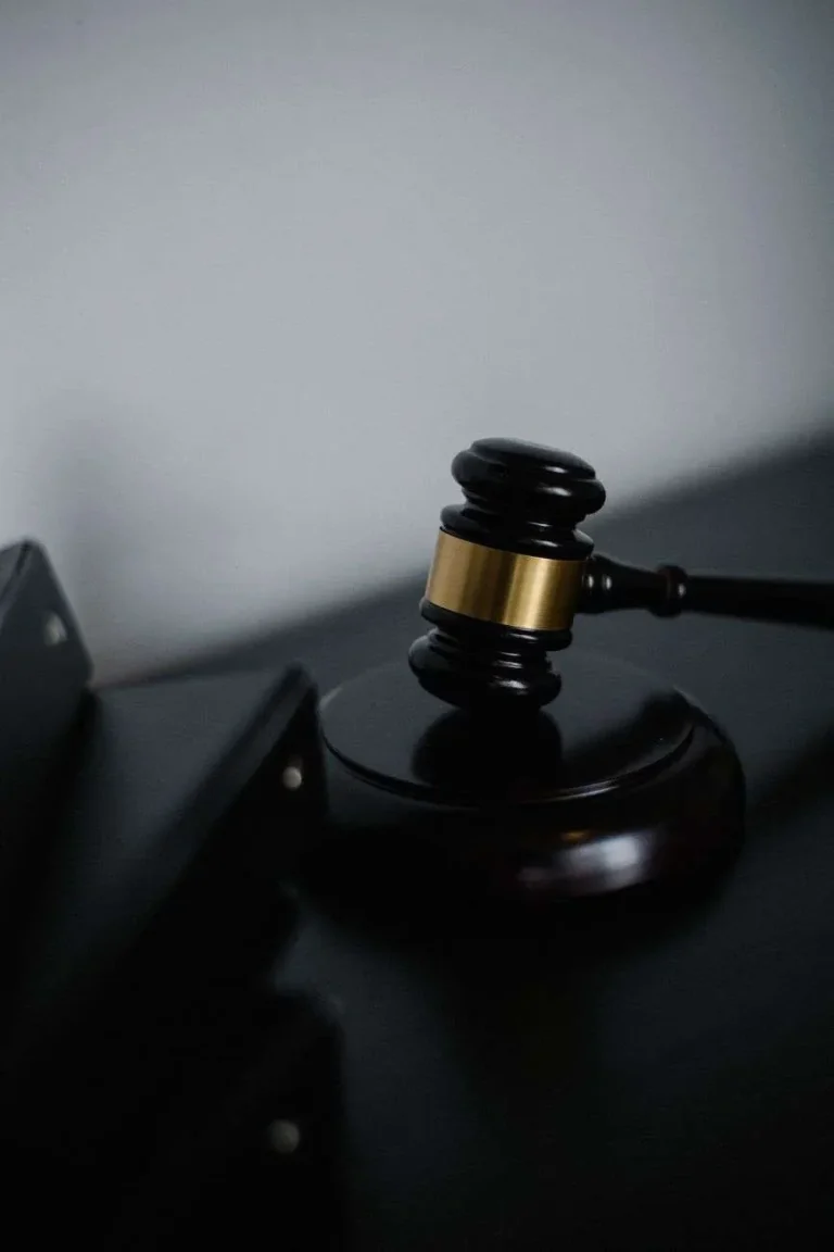 Wooden judges gavel resting on a sound block on a dark surface