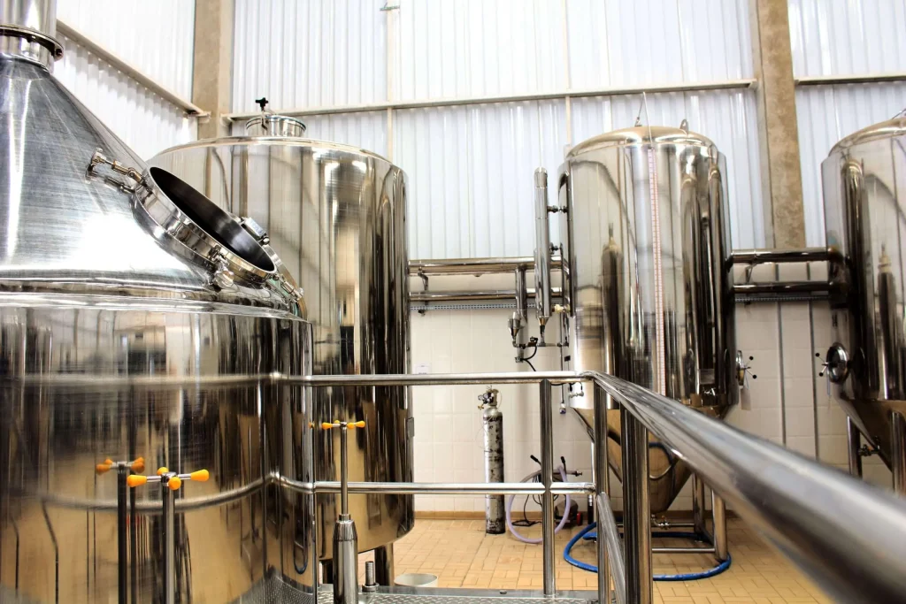 Rows of polished stainless steel brewing and fermentation tanks inside an industrial brewhouse