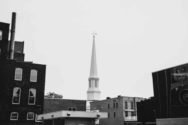 Red brick historic church building with a tall steeple in a downtown setting