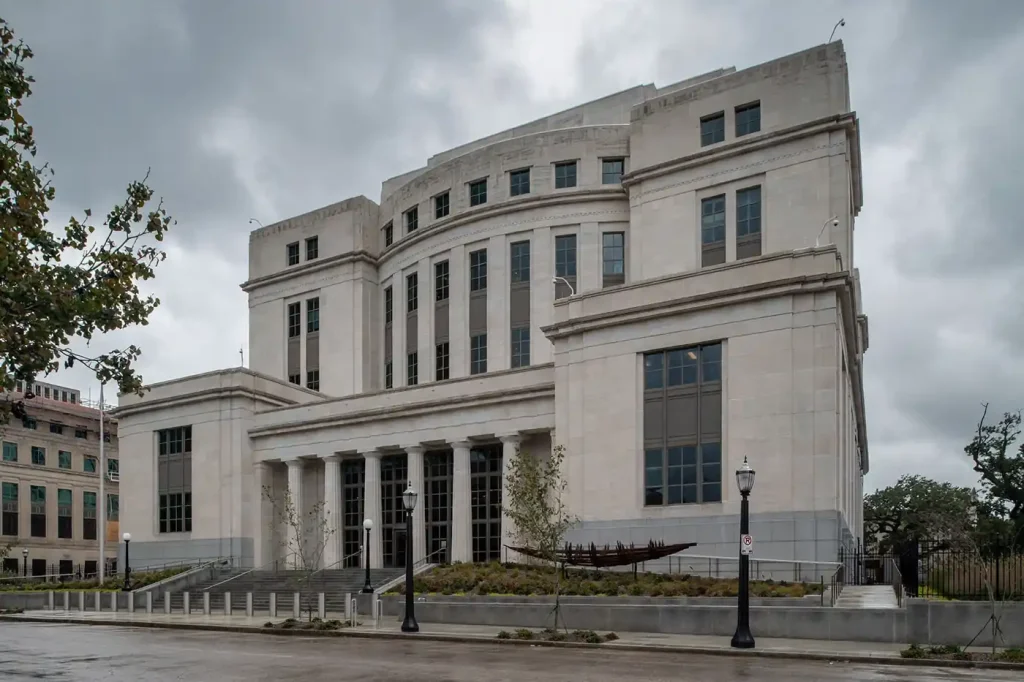 Stone columns and front steps of a federal courthouse under a gray, overcast sky with no people present