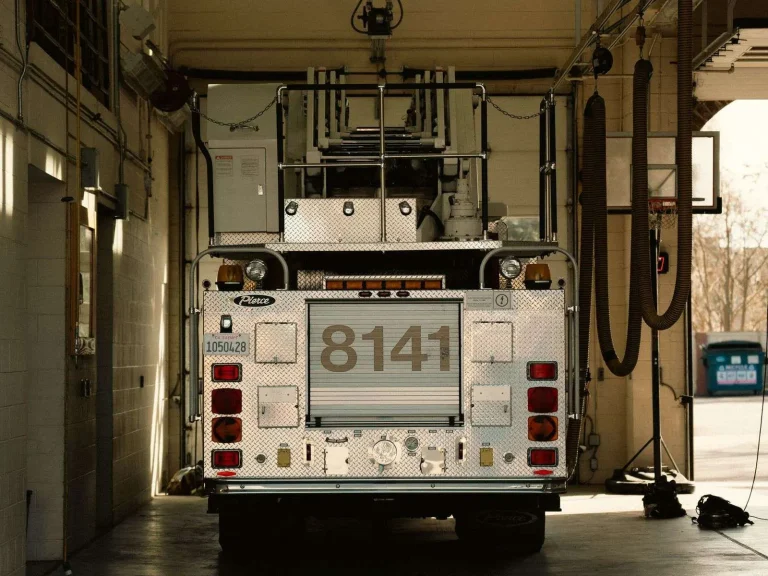 A red fire engine parked inside a fire station garage bay.
