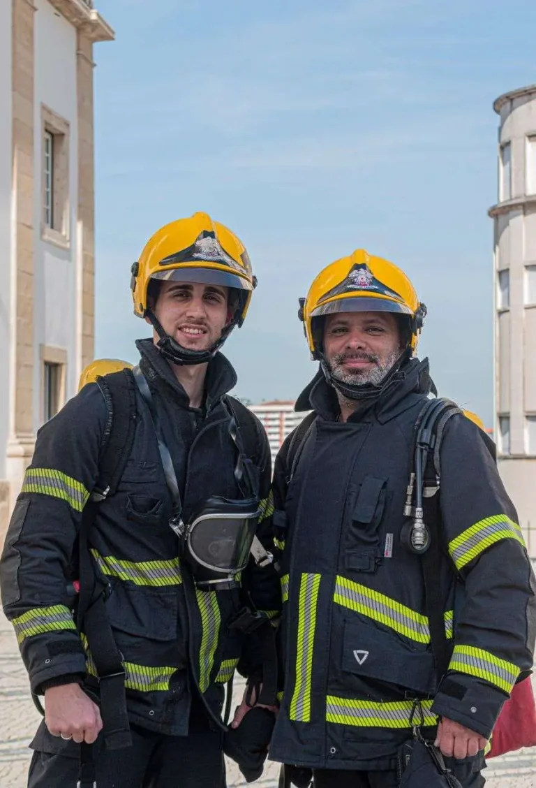 Two firefighters in protective gear and helmets standing side by side
