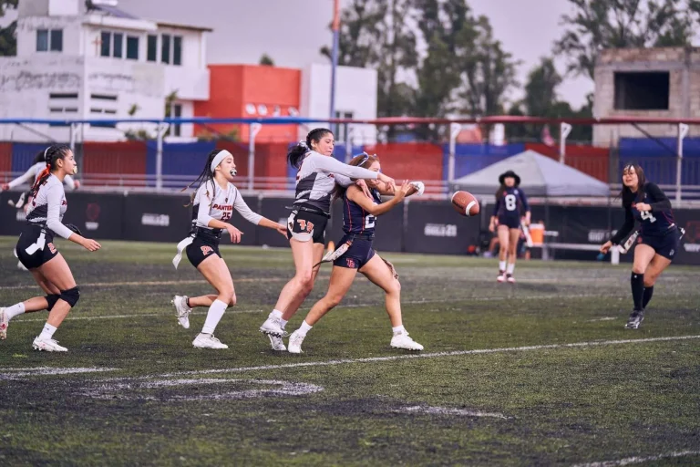 Players in a women's flag football game chasing a pass as the ball flies through the air