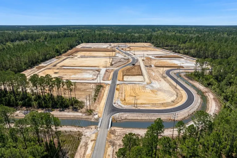 Aerial view of a cleared and graded industrial site with new roads surrounded by pine forest