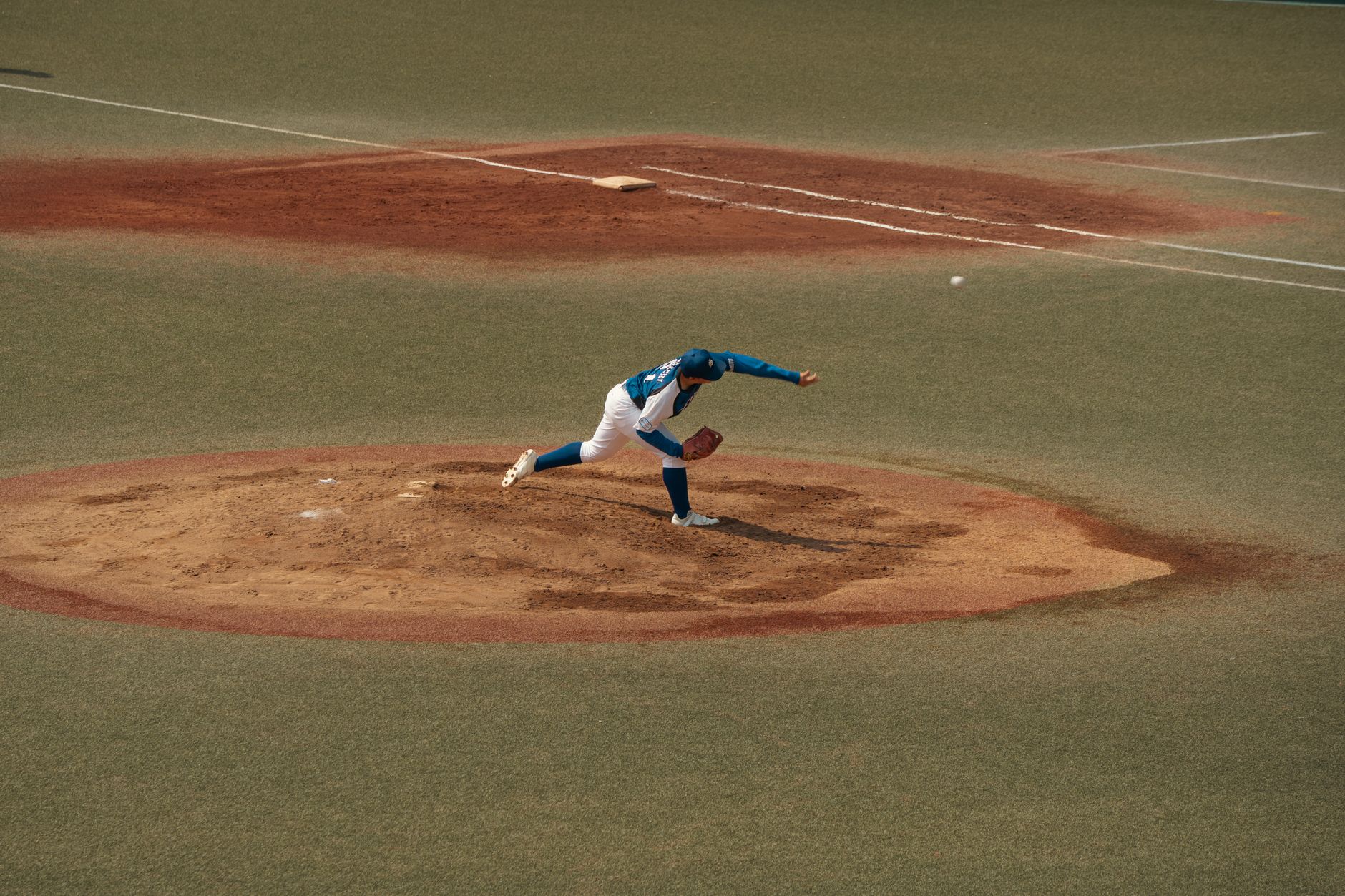 A baseball resting on a pitcher's mound at an empty ballpark