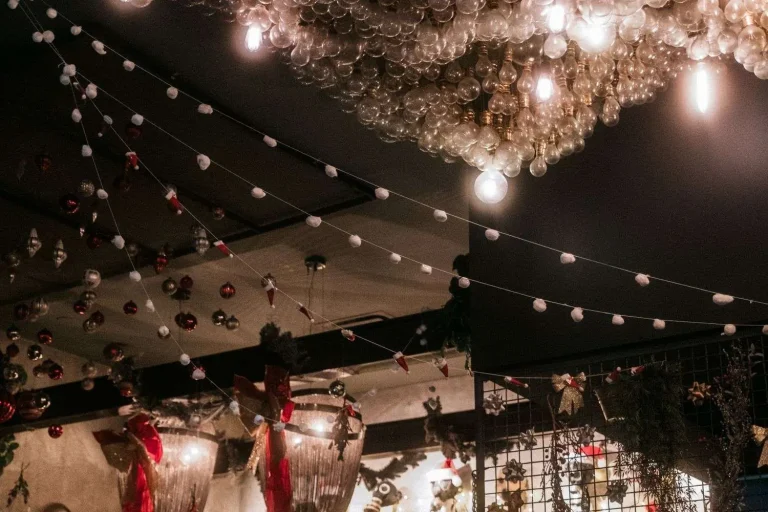 String lights, ornaments and a bulb chandelier decorate the ceiling of a bar during a holiday celebration