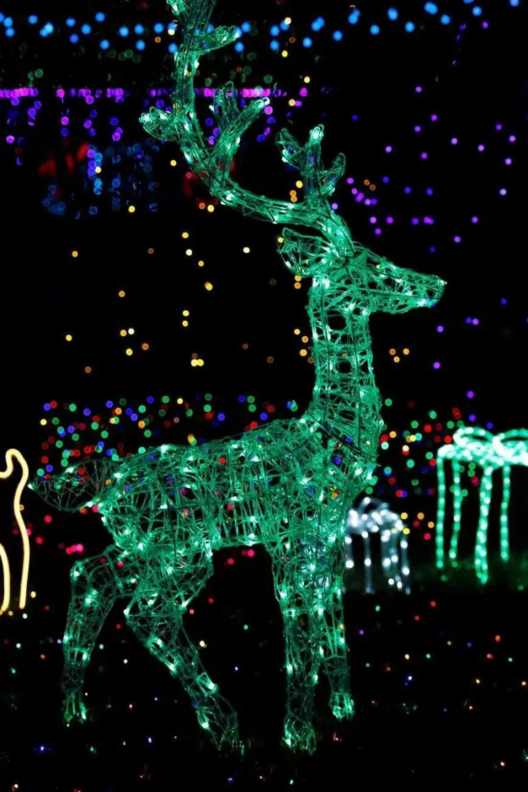 Illuminated deer-shaped light sculpture glowing green amid colorful bokeh lights in a garden at night