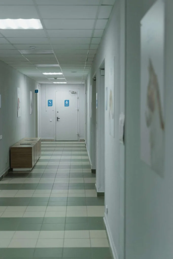 Empty hallway inside a medical clinic with tile flooring and closed doors