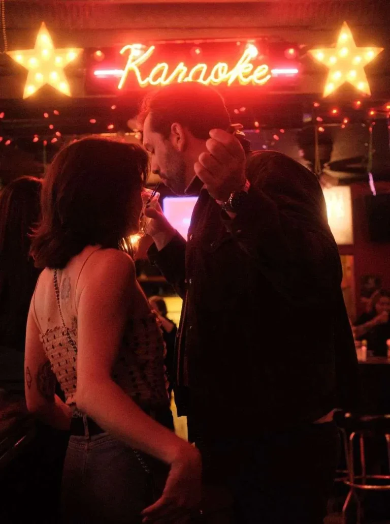 People at a bar counter under a neon Karaoke sign at night