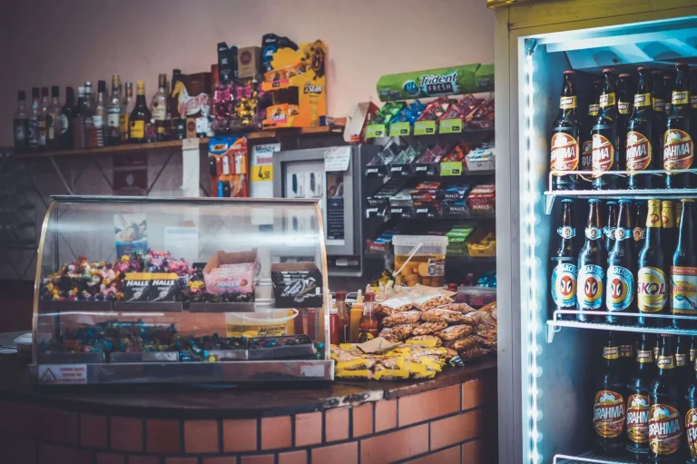 Counter of a convenience/liquor store with shelves of bottled beer and snacks