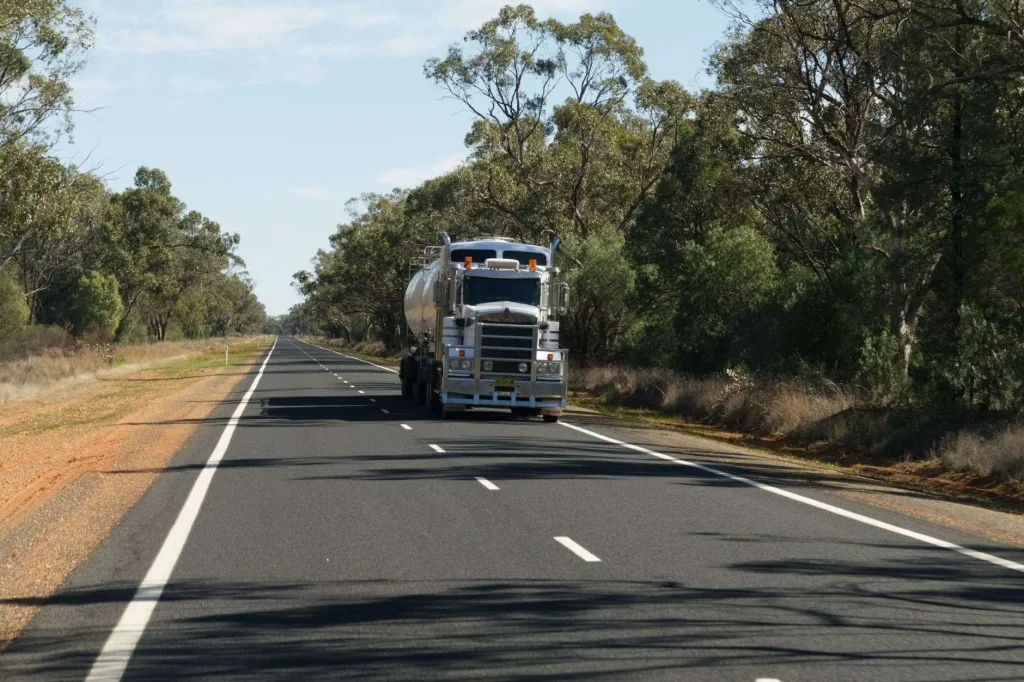 A loaded log truck traveling on a two-lane rural highway