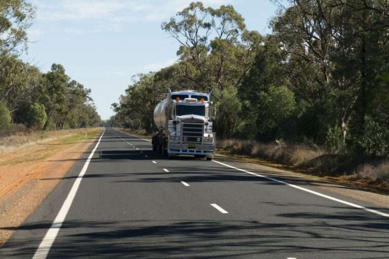 A loaded log truck traveling on a two-lane rural highway
