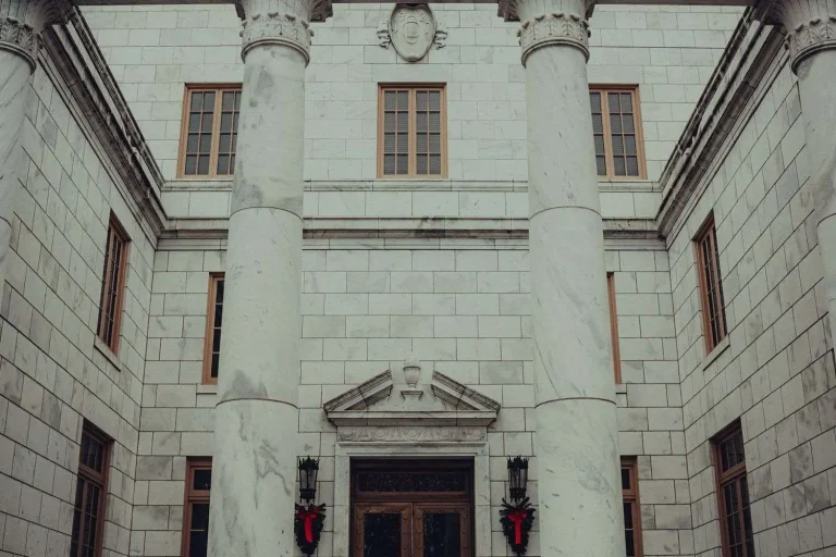 Exterior of a marble courthouse-style building with tall columns and a decorated entrance