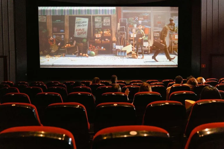 Audience seated in a movie theater watching a film on the big screen