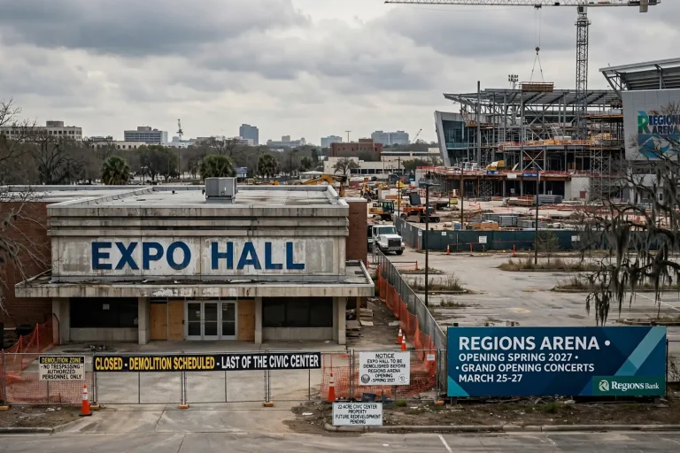 A modern arena under construction beside an older exhibition hall awaiting demolition in downtown Mobile, Alabama