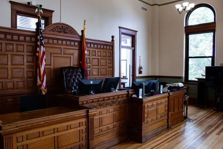 Interior of a courthouse with a judge's bench and flags