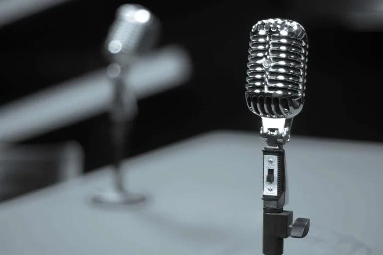 A vintage radio studio microphone with concert lighting in the background