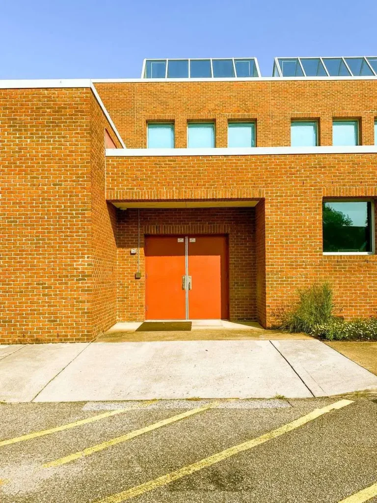 Exterior of a modern brick school building with a red entrance door and windows
