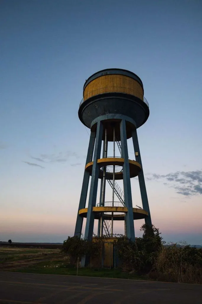 A metal municipal water tower silhouetted against a dusk sky