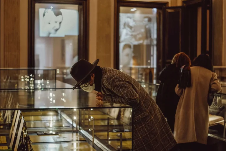 Museum visitors leaning over a lit glass display case examining items inside