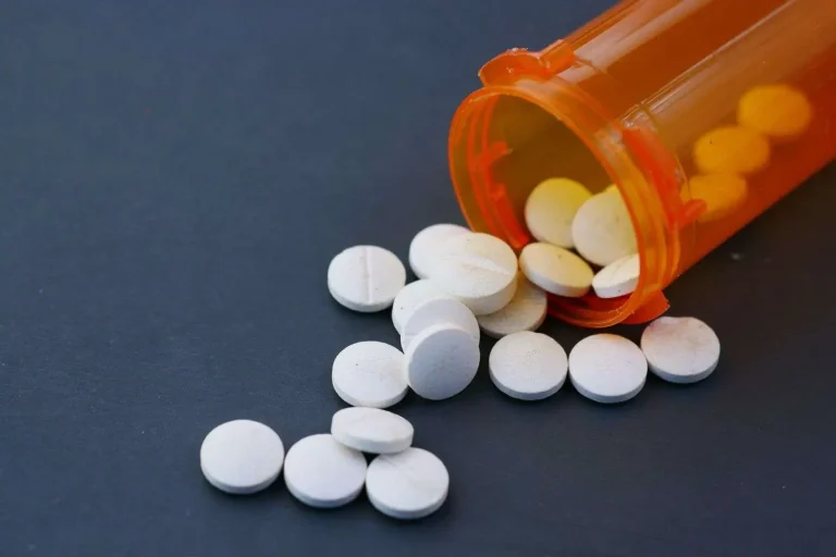 White round tablets spilled out of an open orange prescription pill bottle