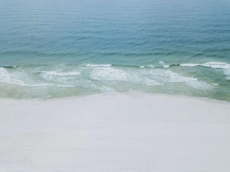 Aerial view of ocean waves washing onto a white sand beach