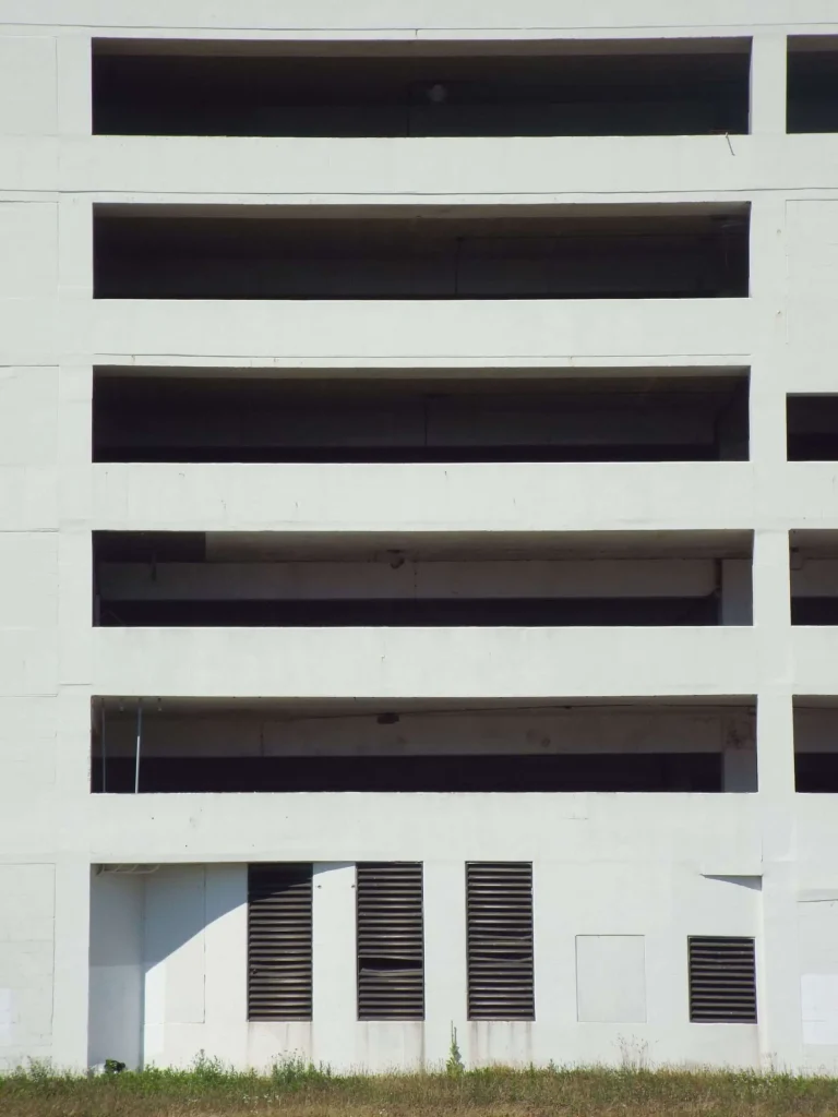 Exterior facade of a multi-level concrete parking garage with open bays