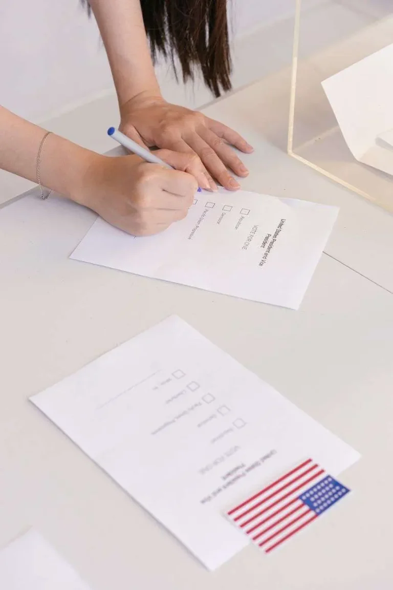 Close-up of a hand marking a party-primary ballot next to a United States flag sticker