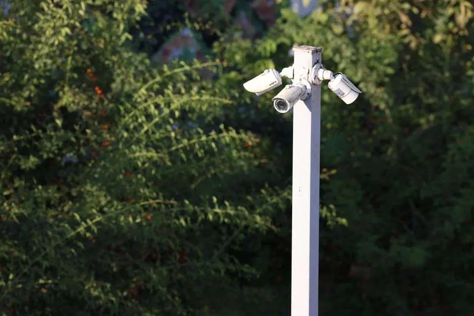 A surveillance camera mounted high on a pole above a street