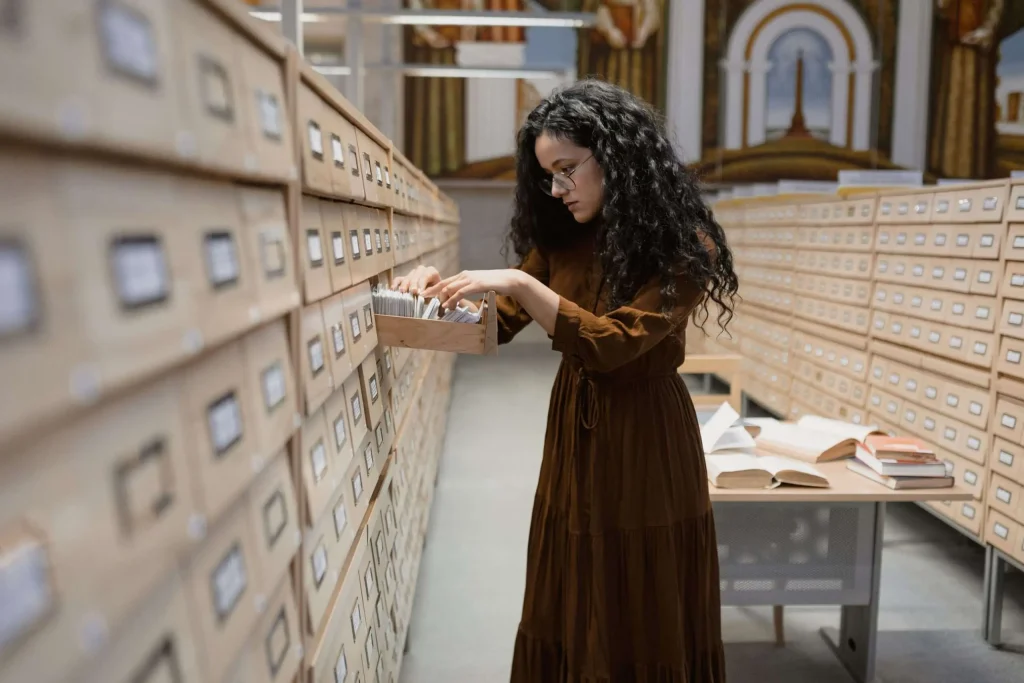 A person browsing historical archive materials and card catalog records in a research library