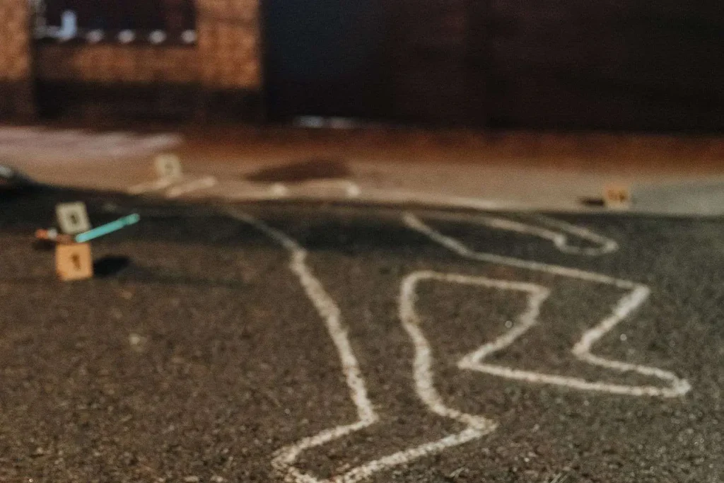 Numbered evidence markers and a chalk outline on pavement at a nighttime crime scene