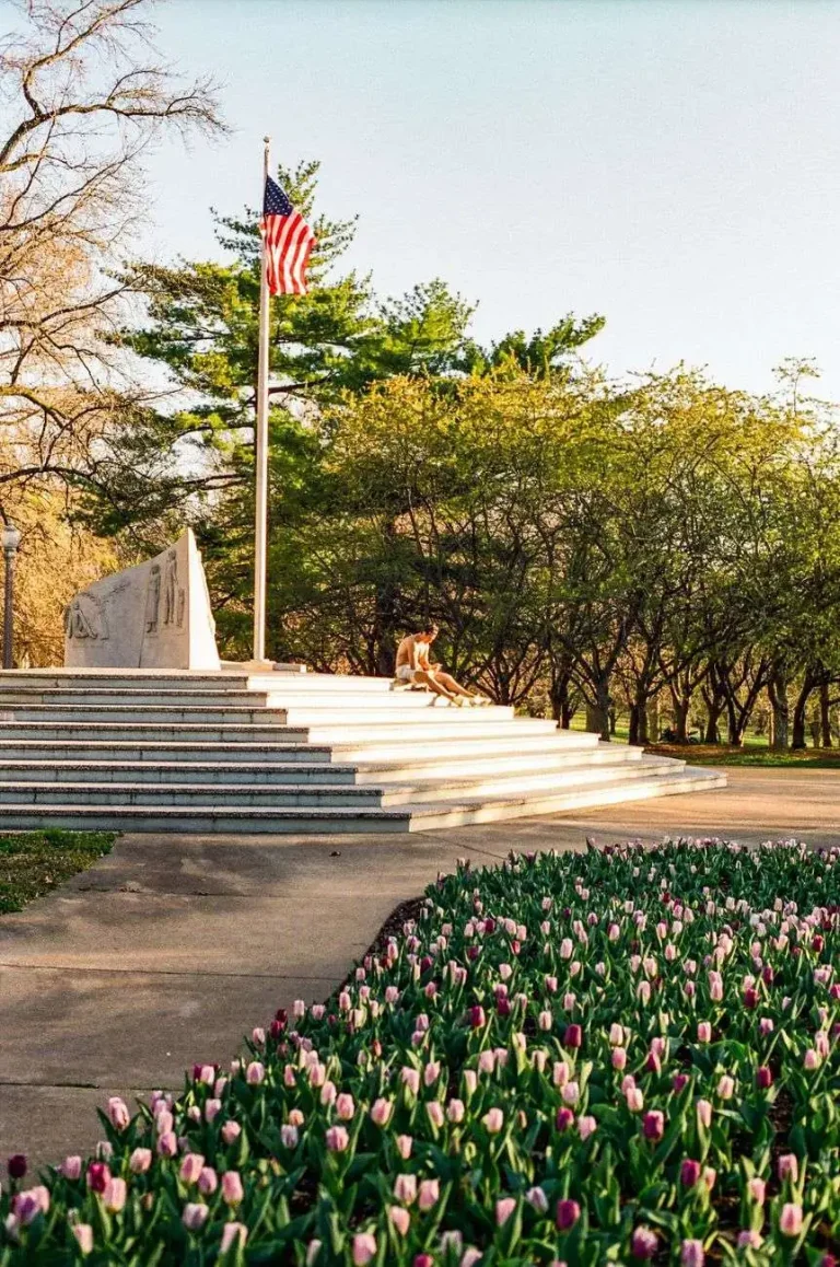 Stone monument with an American flag and steps in a public park