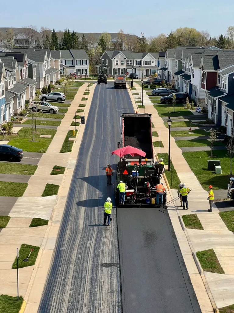 Road crew repaving a residential street in a suburban neighborhood