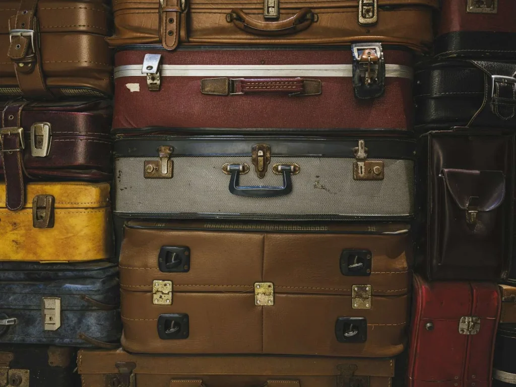 A stack of old vintage suitcases in various colors and materials, piled on top of one another.