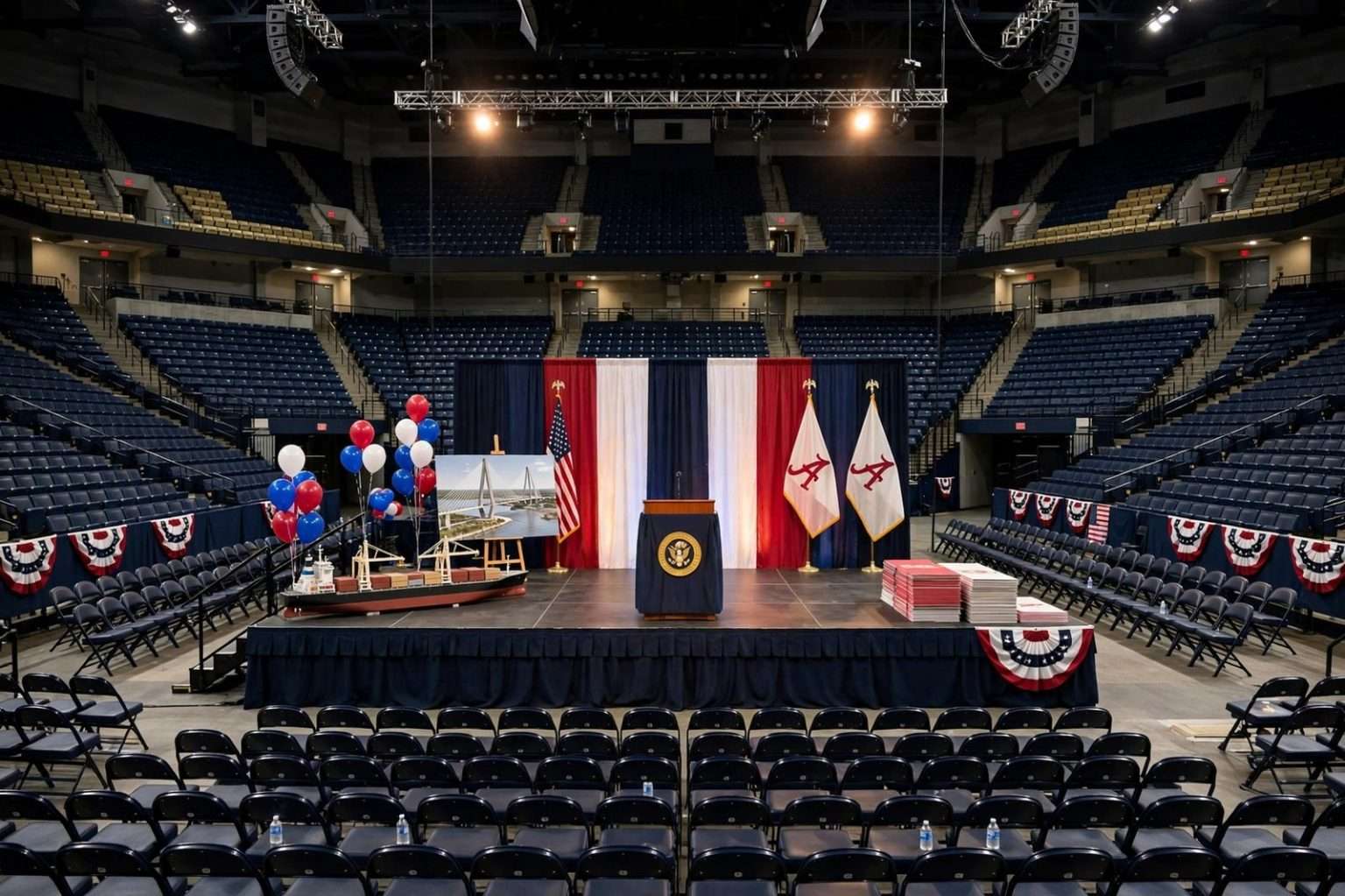 Podium with American flags on a stage inside a crowded college basketball arena lit for an evening political rally