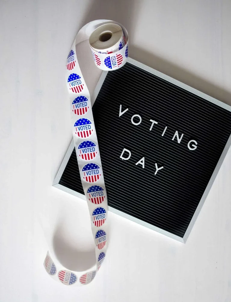 A voting day sign beside a roll of red, white and blue I Voted stickers on a table