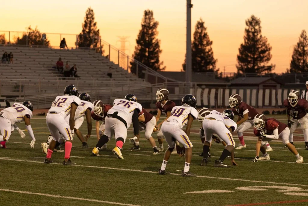 High school football players lined up under stadium lights at night
