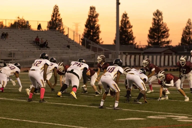 High school football players lined up under stadium lights at night
