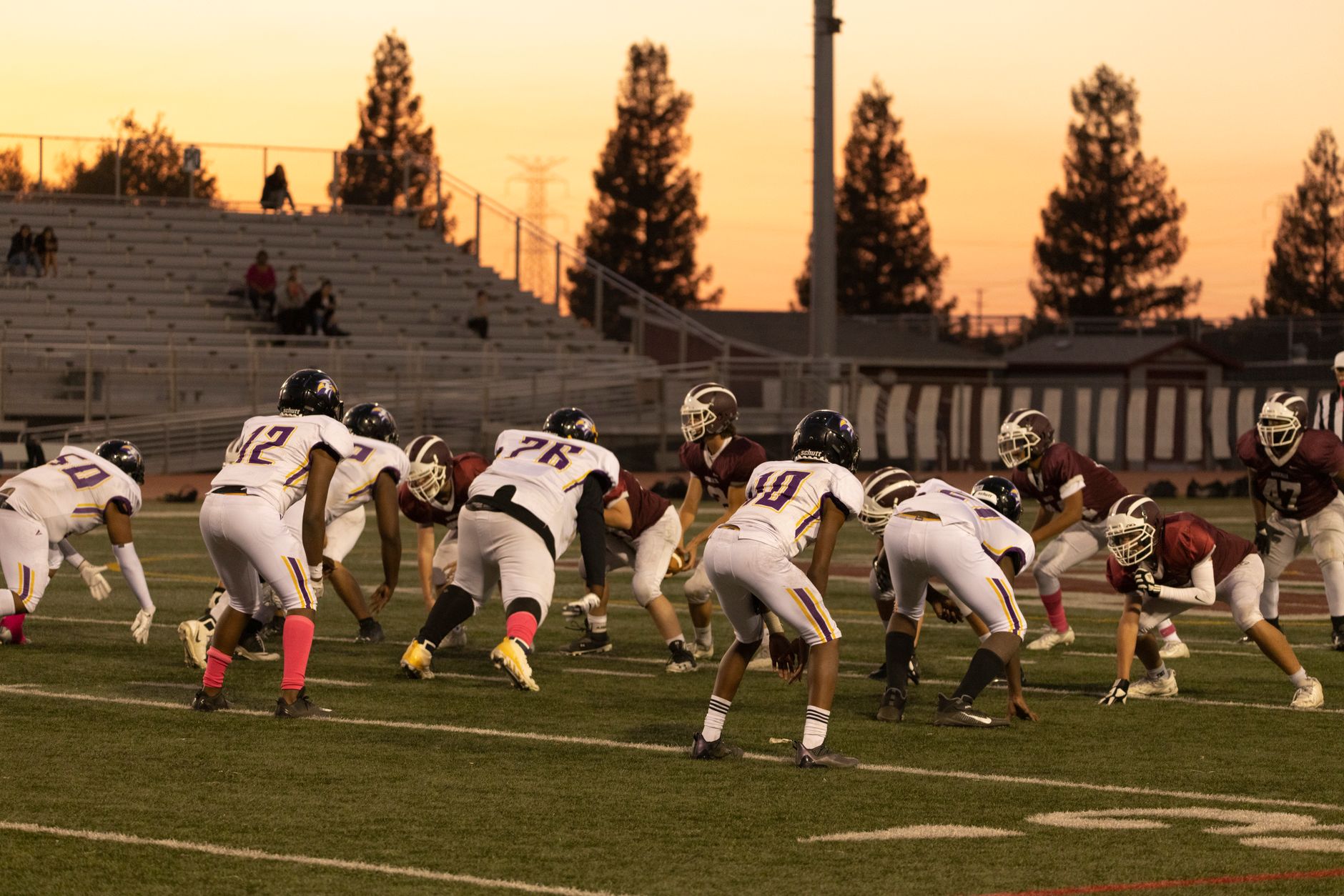 High school football players lined up under stadium lights at night