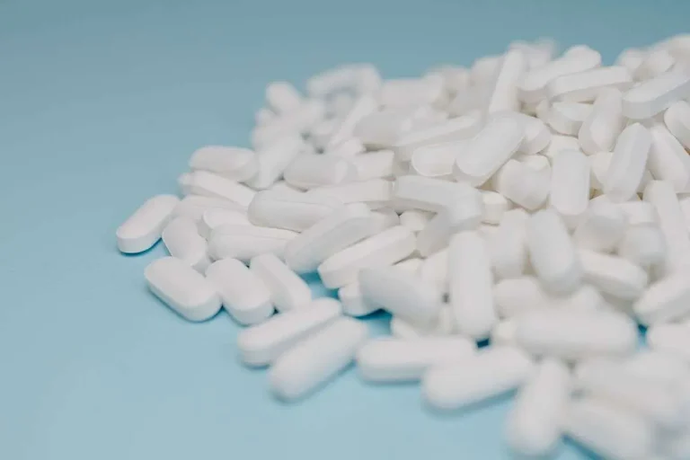Close-up of white pills scattered on a blue surface, representing the dangers of illicit drugs
