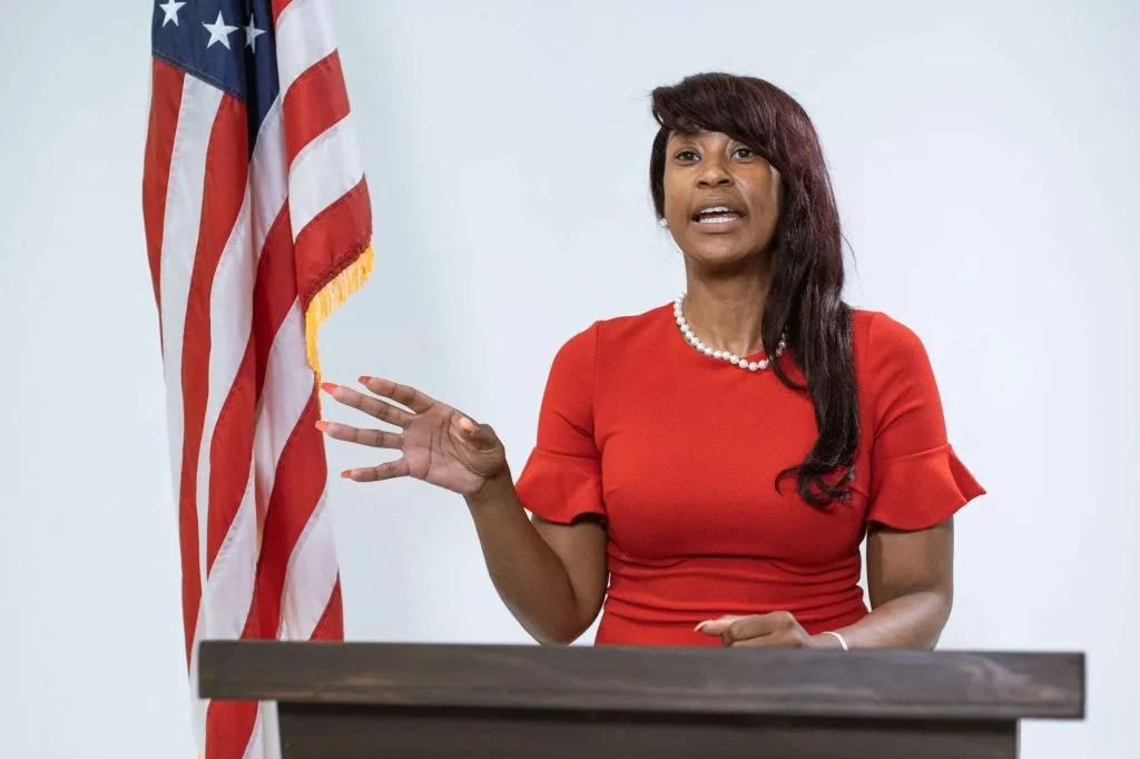A woman speaks at a podium with an American flag beside her