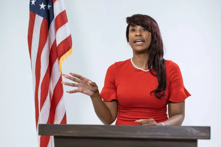 A woman speaks at a podium with an American flag beside her